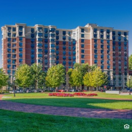 exterior of a building with a grassy area and trees in front of it