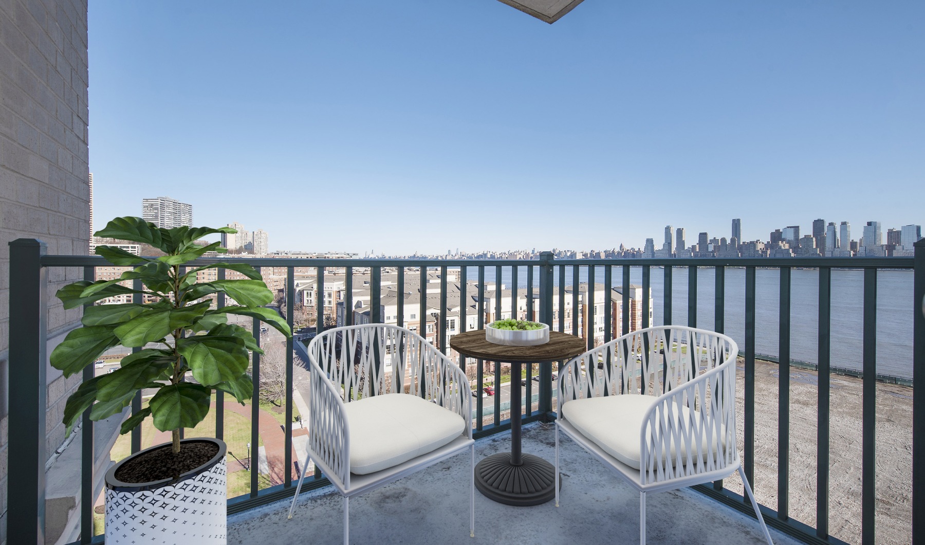 Private balcony at Riverbend at Port Imperial with two chairs and a bistro table overlooking the Hudson River and the Manhattan skyline.